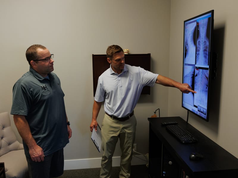 Doctor reviewing a patient's cervical spine X-ray as part of a neck and migraine evaluation
